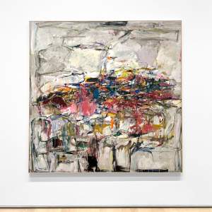 City Landscape is an abstract painting composed of a central tangle of vibrant colors—purple, pink, orange, green, red—on a mostly gray background, subtly divided into rectangular areas. It is shown hanging on a white gallery wall over a wooden floor.